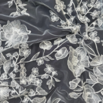 Vibrant off white tulle fabric adorned with intricate floral embroidery
